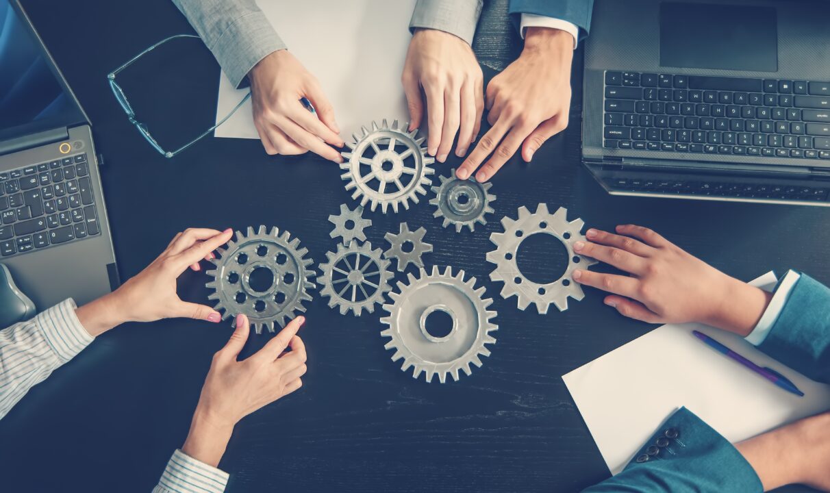 Hands assembling gears on a table.