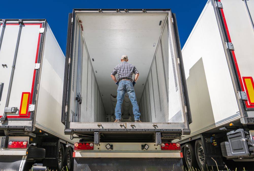 Person standing inside an open truck trailer.